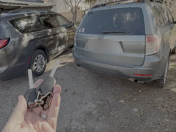 New Subaru keys in hand next to a Subaru Forester and the Spare Me Car Keys van